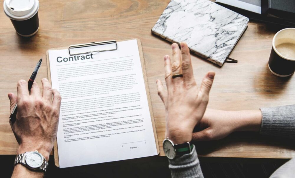 Hands holding a printed cover letter beside a laptop