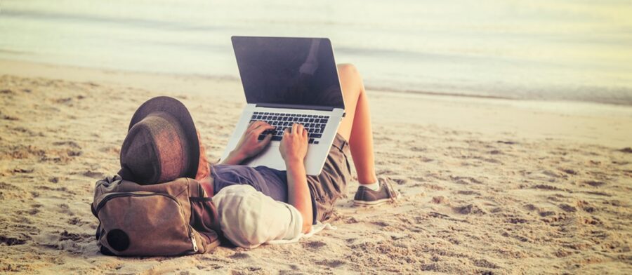 Person working remotely on a laptop from bed
