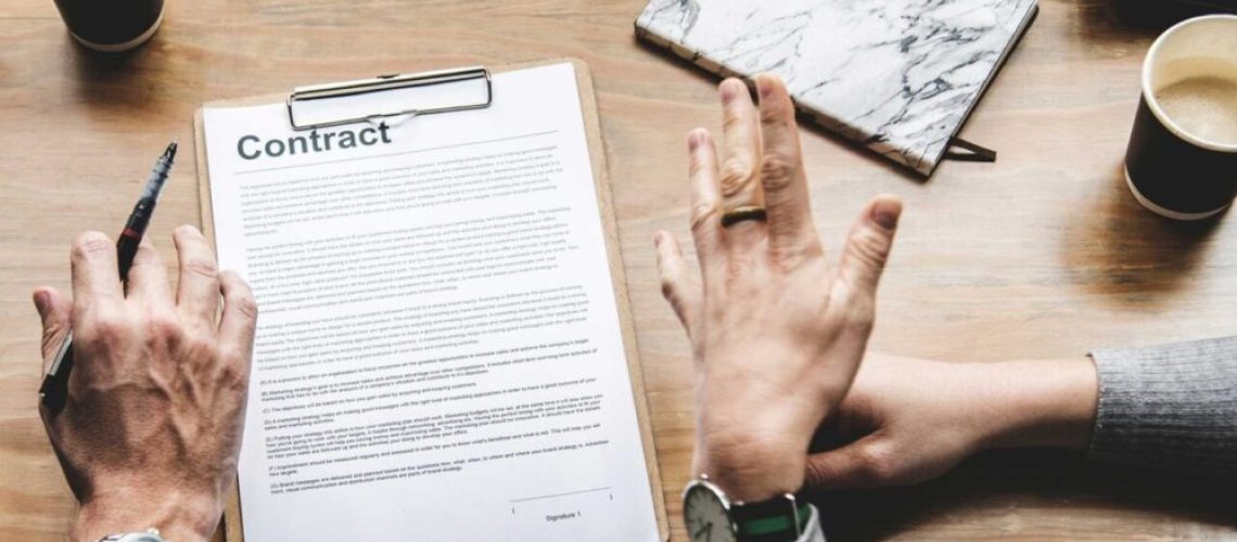 Hands holding a printed cover letter beside a laptop