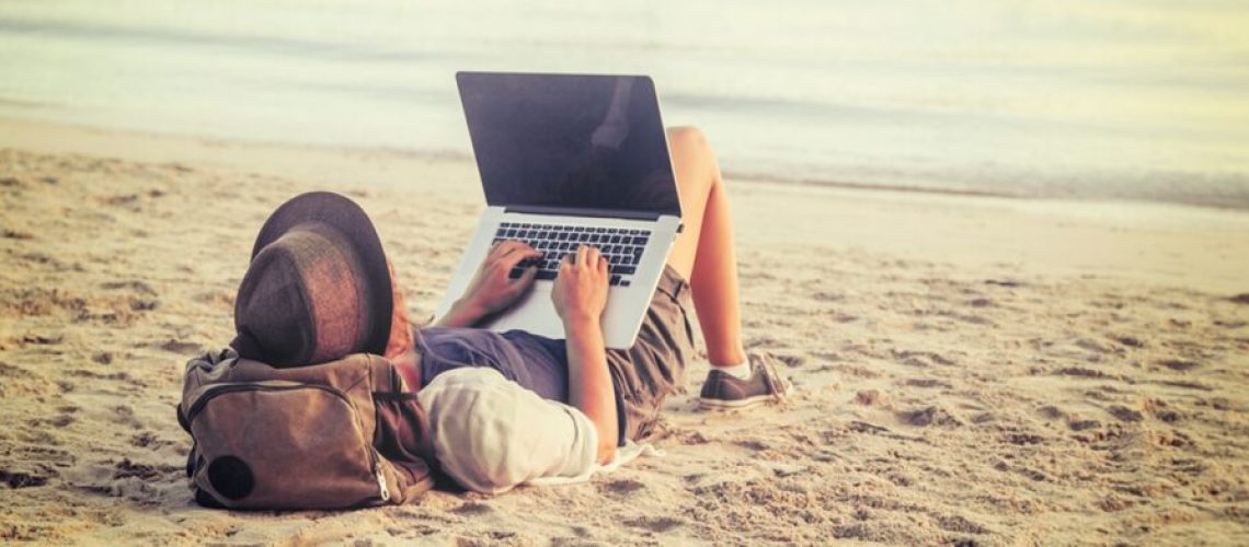 Person working remotely on a laptop from bed